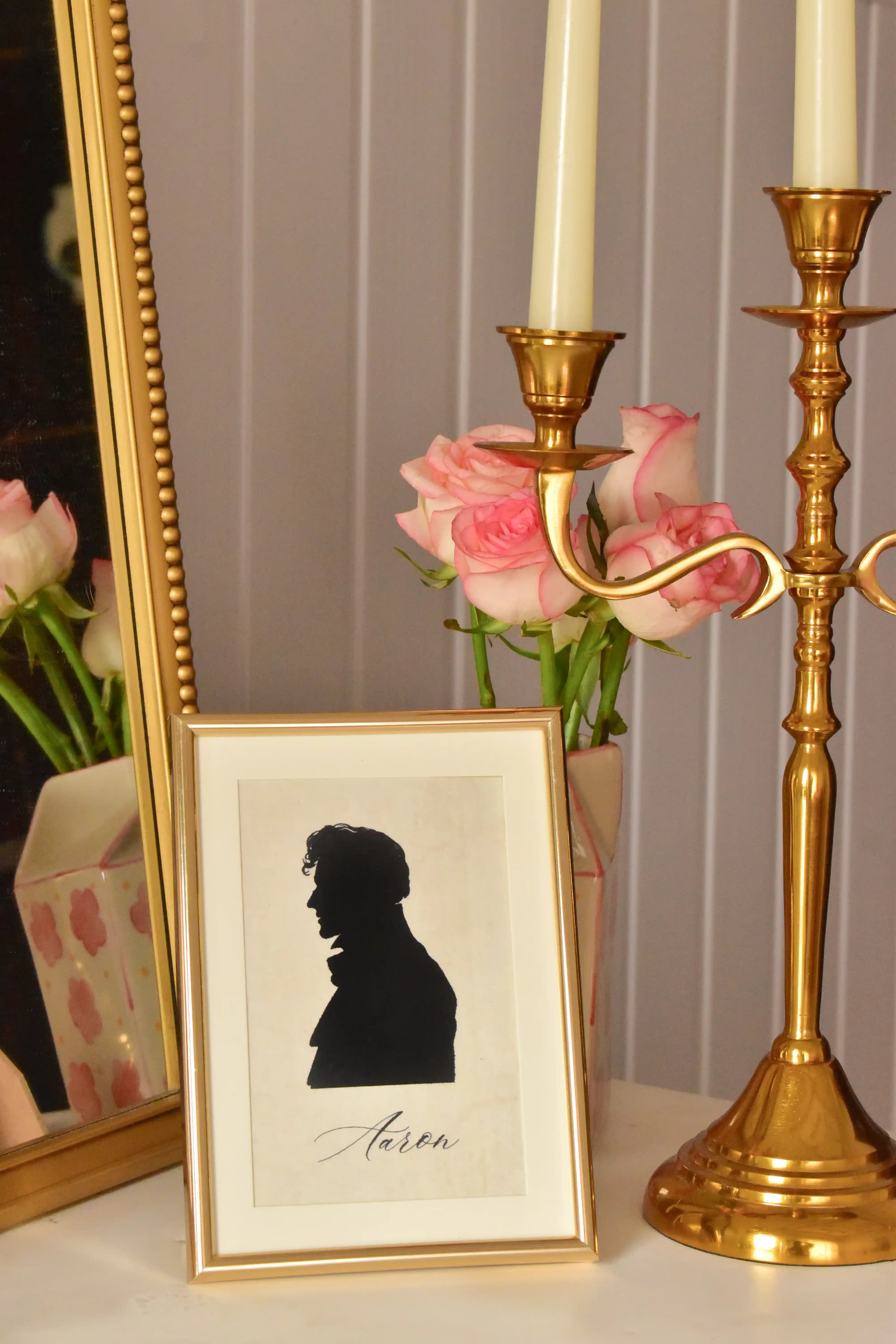 Custom black silhouette portrait of a man, named 'Aaron,' in a golden frame, displayed with a gold candelabra.