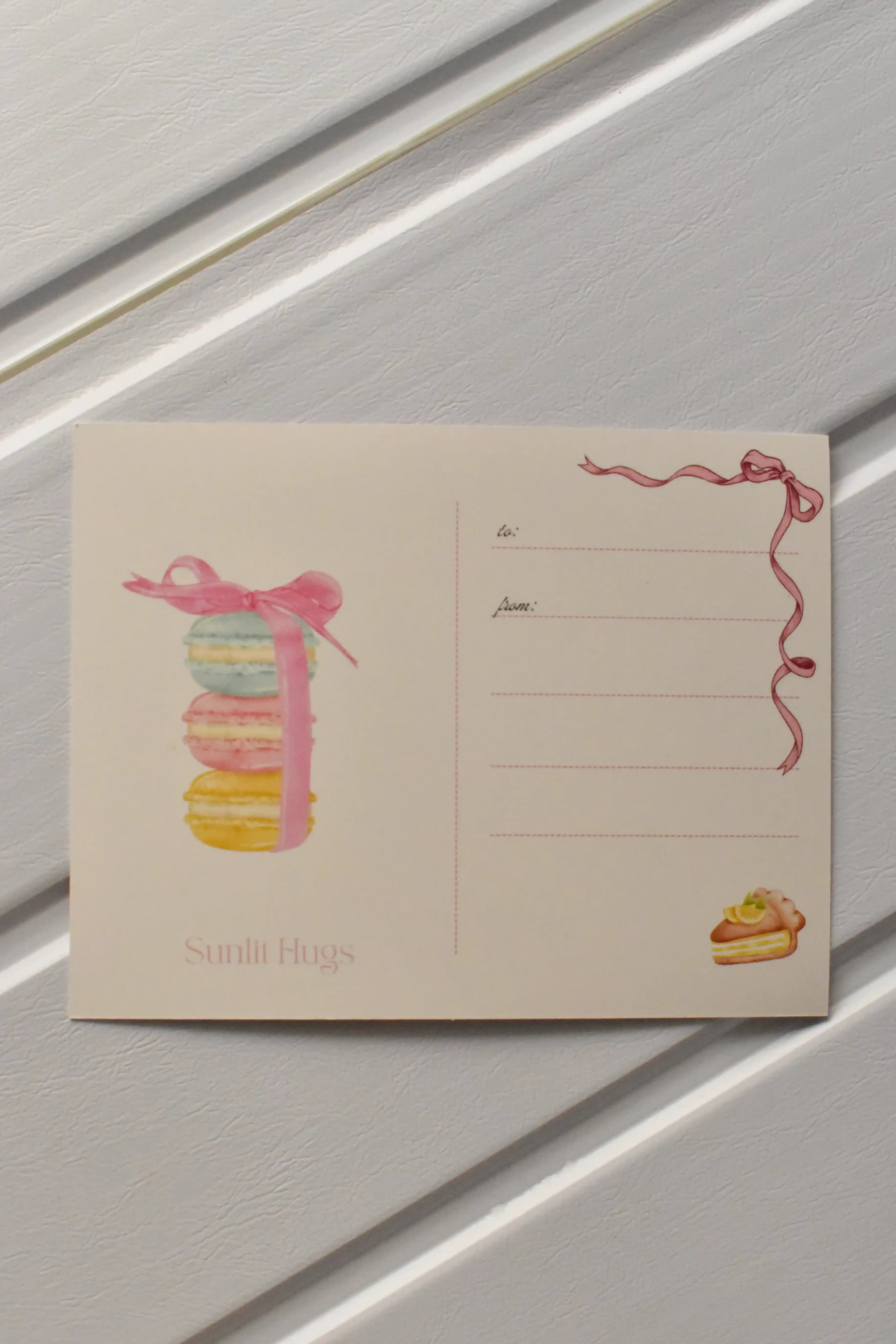 This image focuses on the reverse of the postcard, highlighting the beautiful macaron stack illustration that adds a sweet touch before the postcard is sent to a loved one.