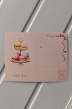 This image focuses on the reverse of the postcard, highlighting the beautiful macaron stack illustration that adds a sweet touch before the postcard is sent to a loved one.
