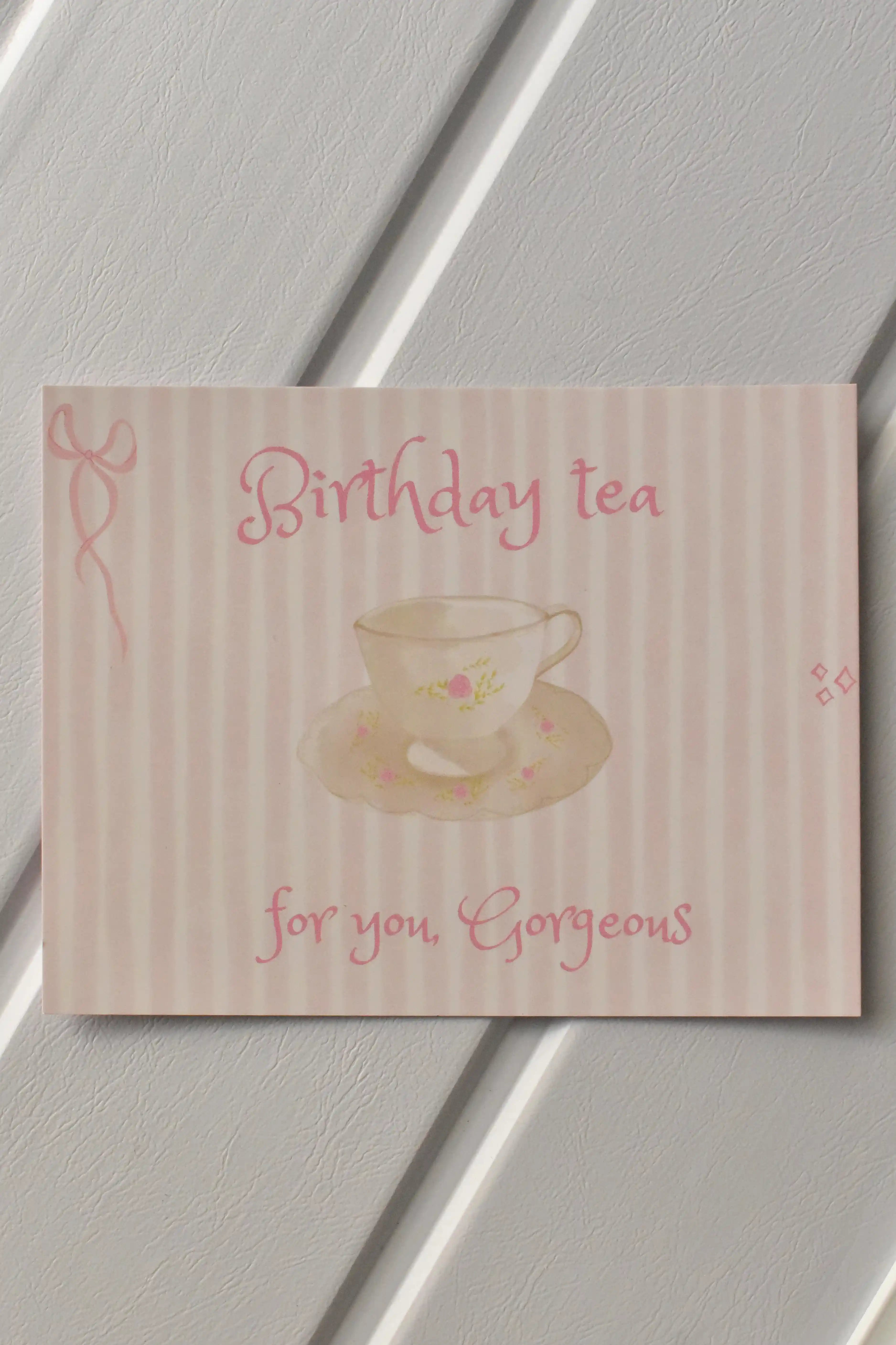 This image shows a beautiful, detailed view of the front of the Birthday Tea Postcard, highlighting the delicate pink striped design and the whimsical teacup illustration—a perfect warm invitation.