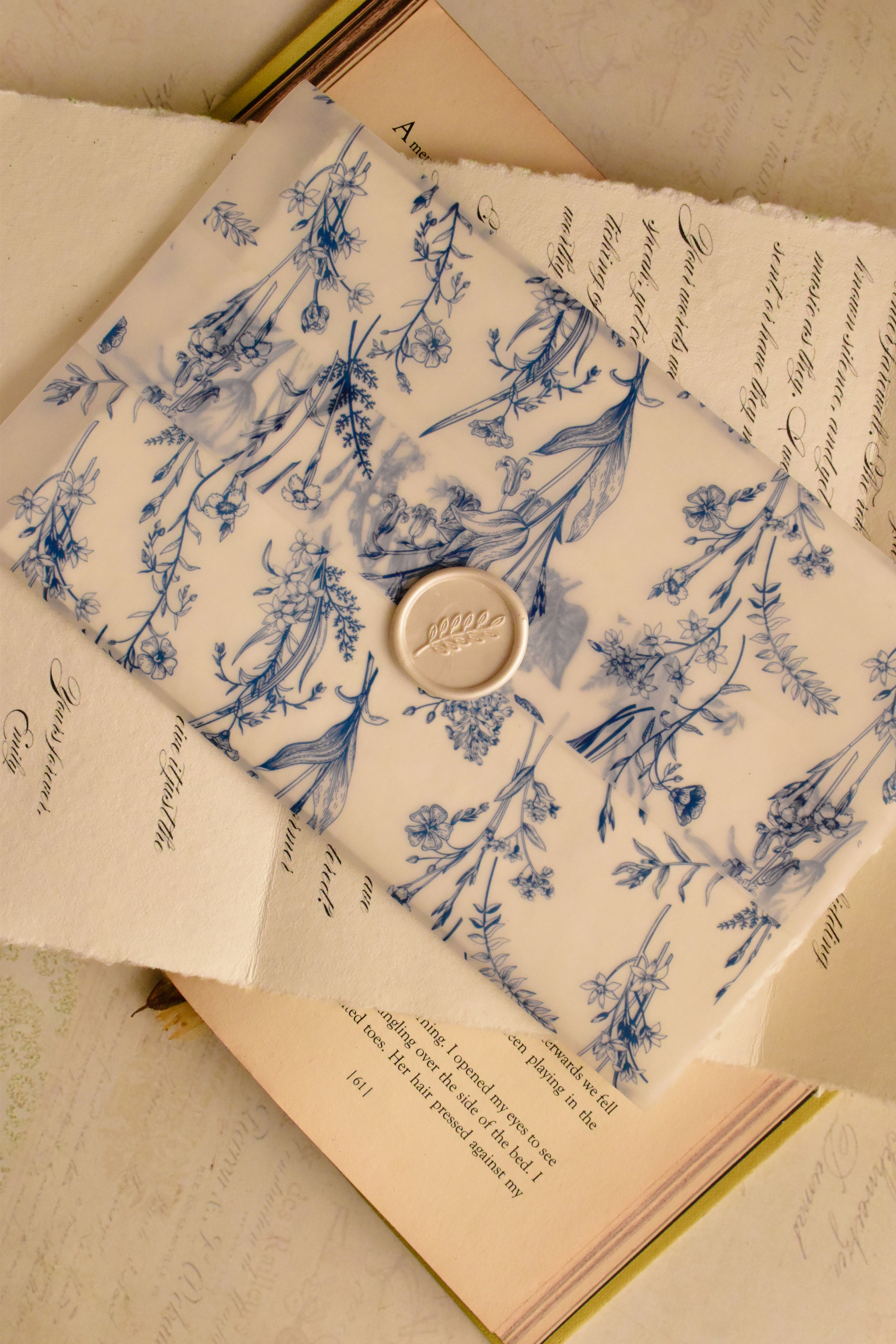 A unique layering shot showing the semi-transparent blue floral vellum resting on the elegant vintage calligraphy of the personalised message, creating a beautiful piece of romantic art.