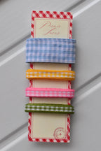 Four narrow gingham ribbons in blue, yellow, pink, and green colours, displayed vertically on a themed ribbon card.
