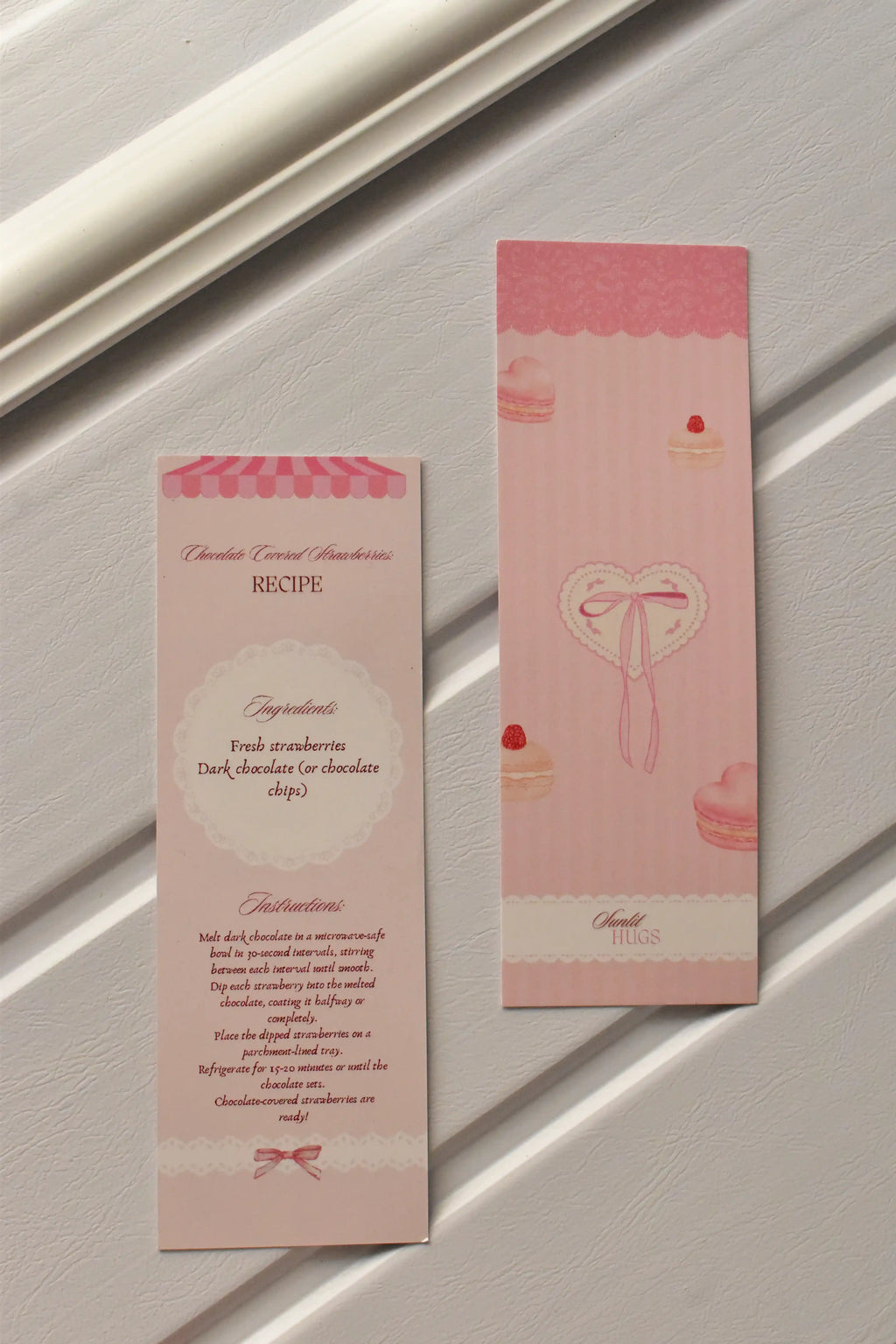 This side-by-side image highlights the unique design, pairing the Macaron and Heart illustration on the front with the full Chocolate Covered Strawberries Recipe on the reverse.