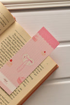This warm shot demonstrates the bookmark in action, showing the macaron and heart design tucked inside a book, perfect for marking your place during a moment of sweet indulgence.