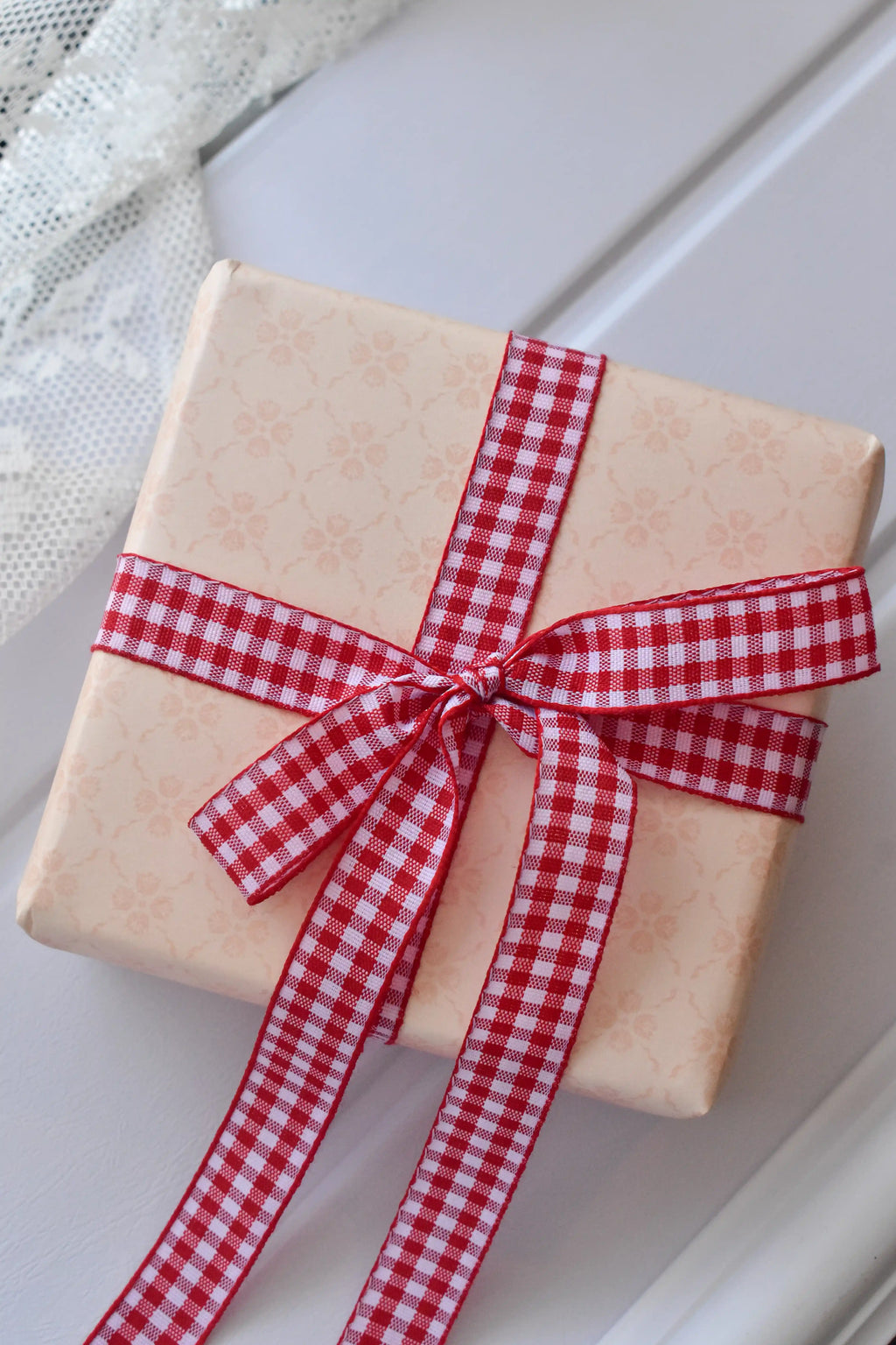 This image shows the Cherry Picnic Wide ribbon tied around a gift, demonstrating how its red and white checkered design and broad width can create a bold, beautiful bow for presenting gifts.