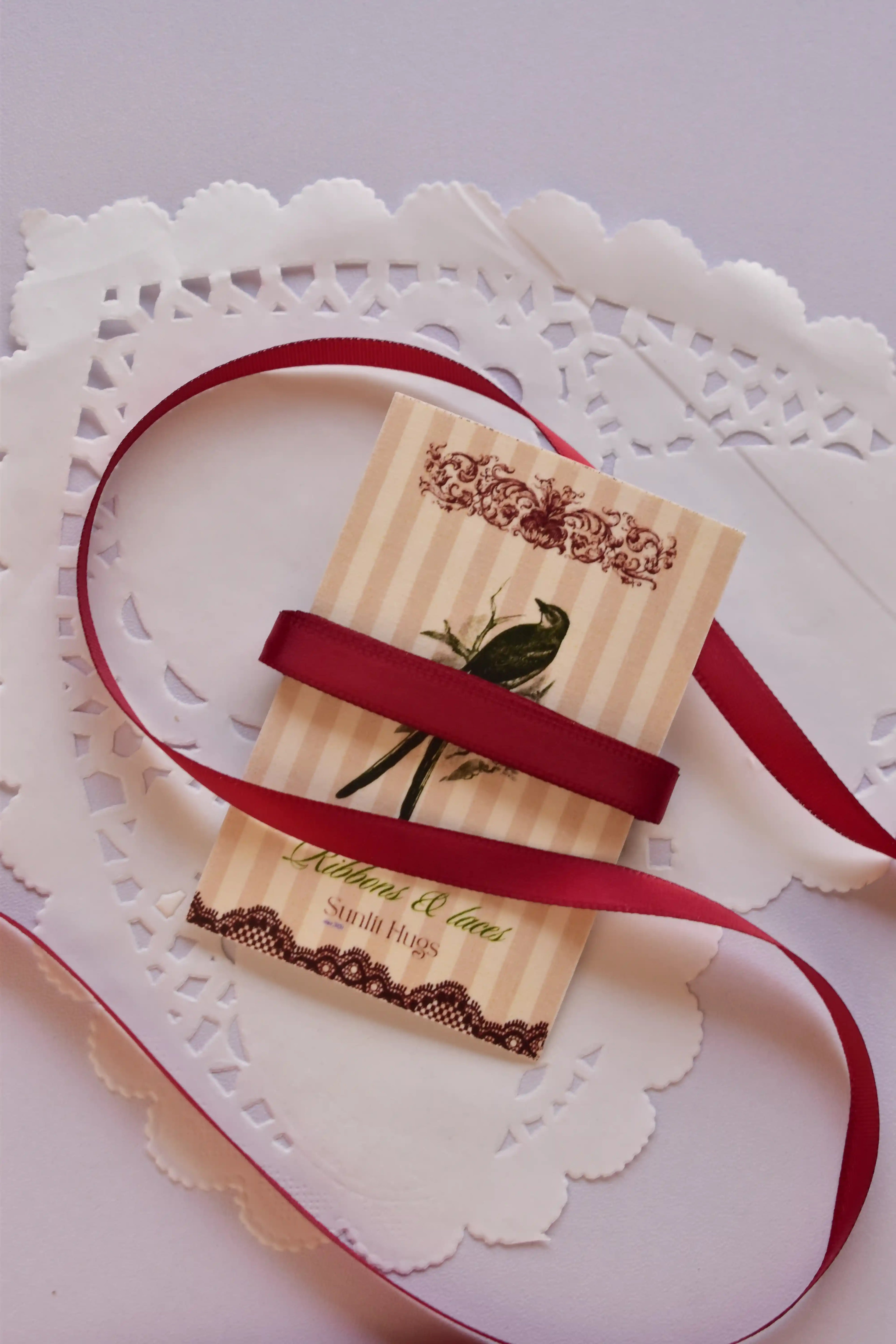 Narrow cherry red satin ribbon (6mm, 2 Metres) wrapped tightly across a "Sunlit Hugs" card, highlighting the sleek, smooth texture.