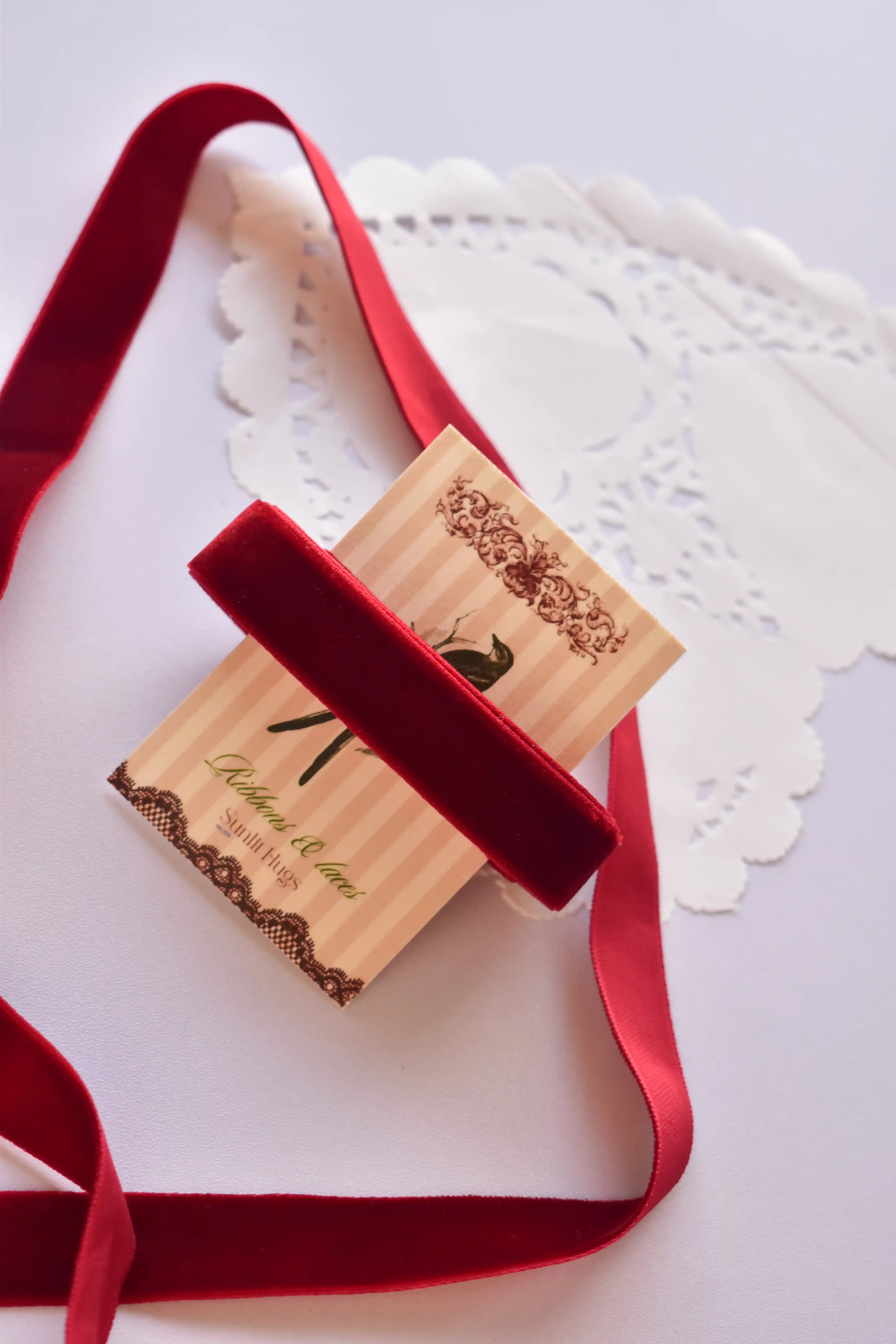Wide cherry red velvet ribbon (15mm, 2 Metres) draped elegantly around a "Sunlit Hugs" card with a long, loose strand flowing down.
