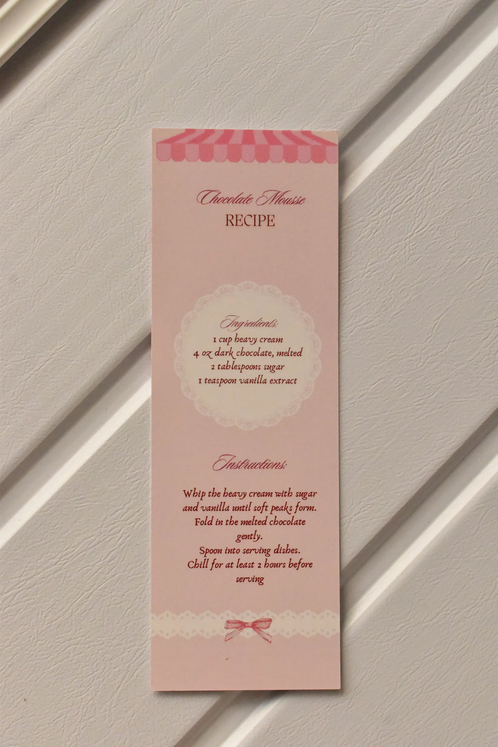 This image focuses on the practical element, displaying the detailed Chocolate Mousse Recipe printed on the back of the pastel pink bookmark.