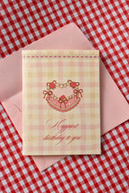 This image shows the front of the 'Happiest Birthday to You' card, featuring the nostalgic strawberry heart cake design and pink and cream gingham pattern from the set.