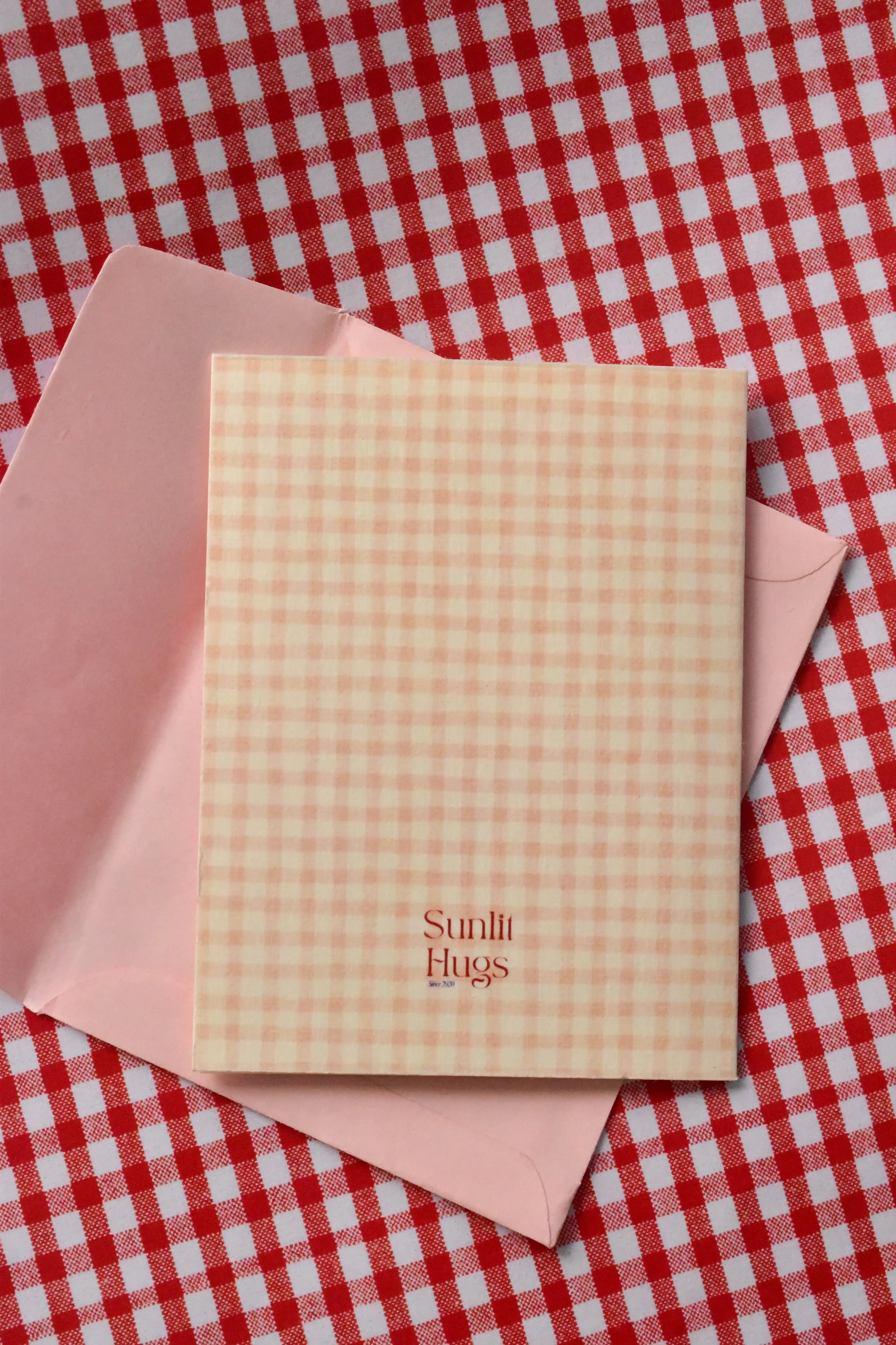 This image displays the back of the Happy Birthday Cutie card. The continuous pink and cream gingham design and the Sunlit Hugs logo are visible, reinforcing the charming, cohesive look.