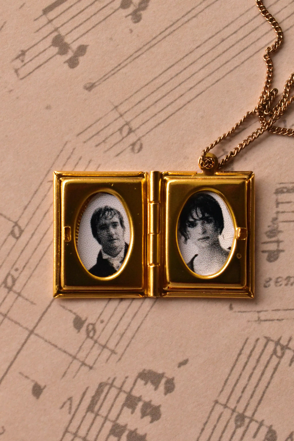 This angled image captures the open golden alloy locket, demonstrating how beautifully the black and white photos sit within the vintage frames. (Note: Chain is for visual purposes only).