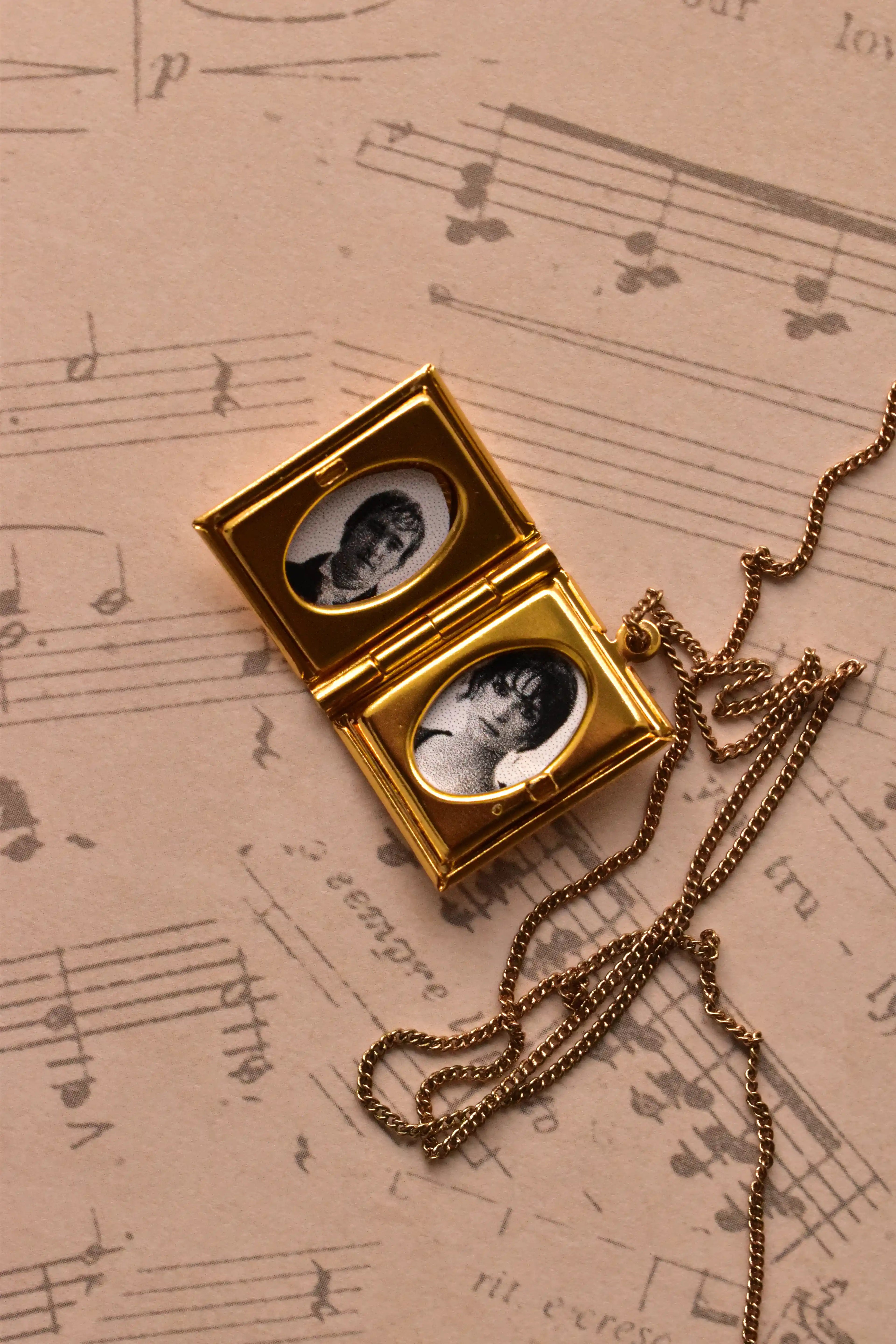 A detailed view of the open golden alloy locket, showcasing the quality of the two custom inserted black and white photographs, ready to preserve a precious moment.