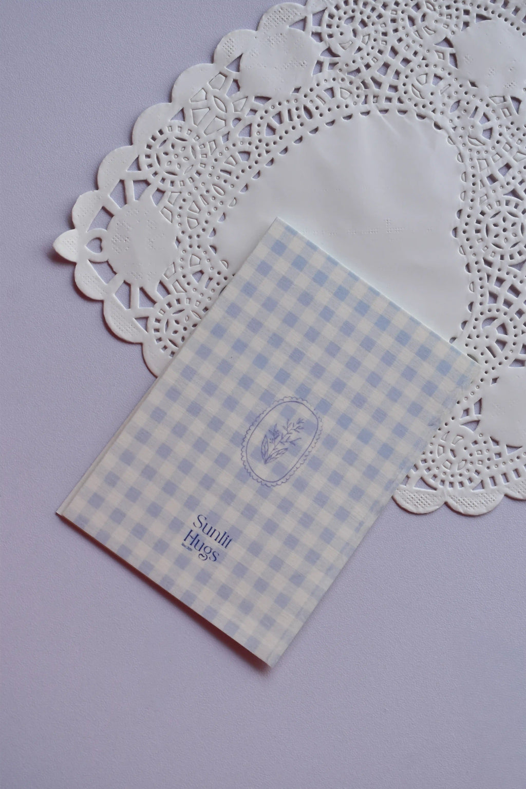 Back of the Mini Wishing Picnics Card featuring a blue gingham pattern with a small floral accent, resting on a white lace doily.