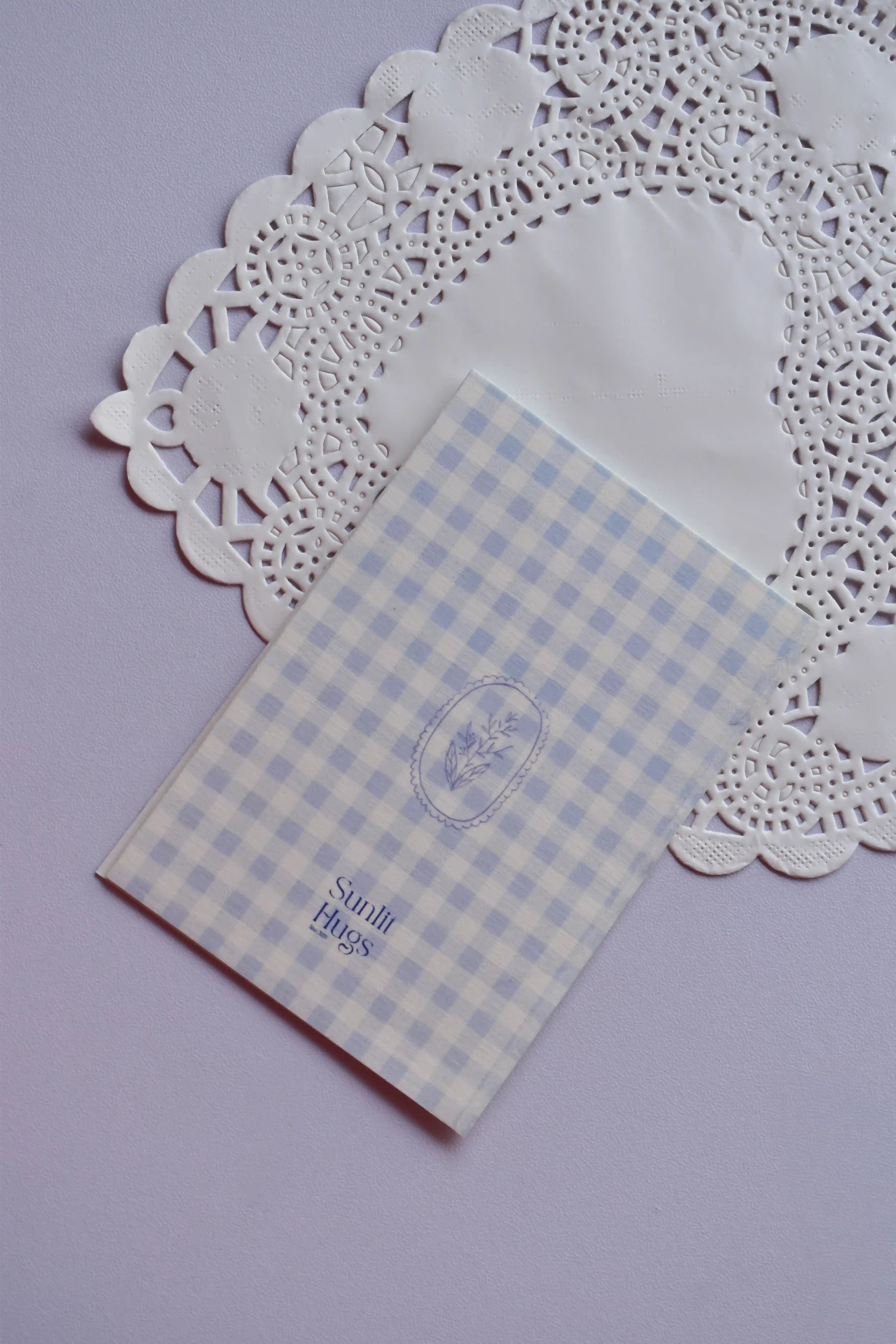 Back of the Mini Wishing Picnics Card featuring a blue gingham pattern with a small floral accent, resting on a white lace doily.
