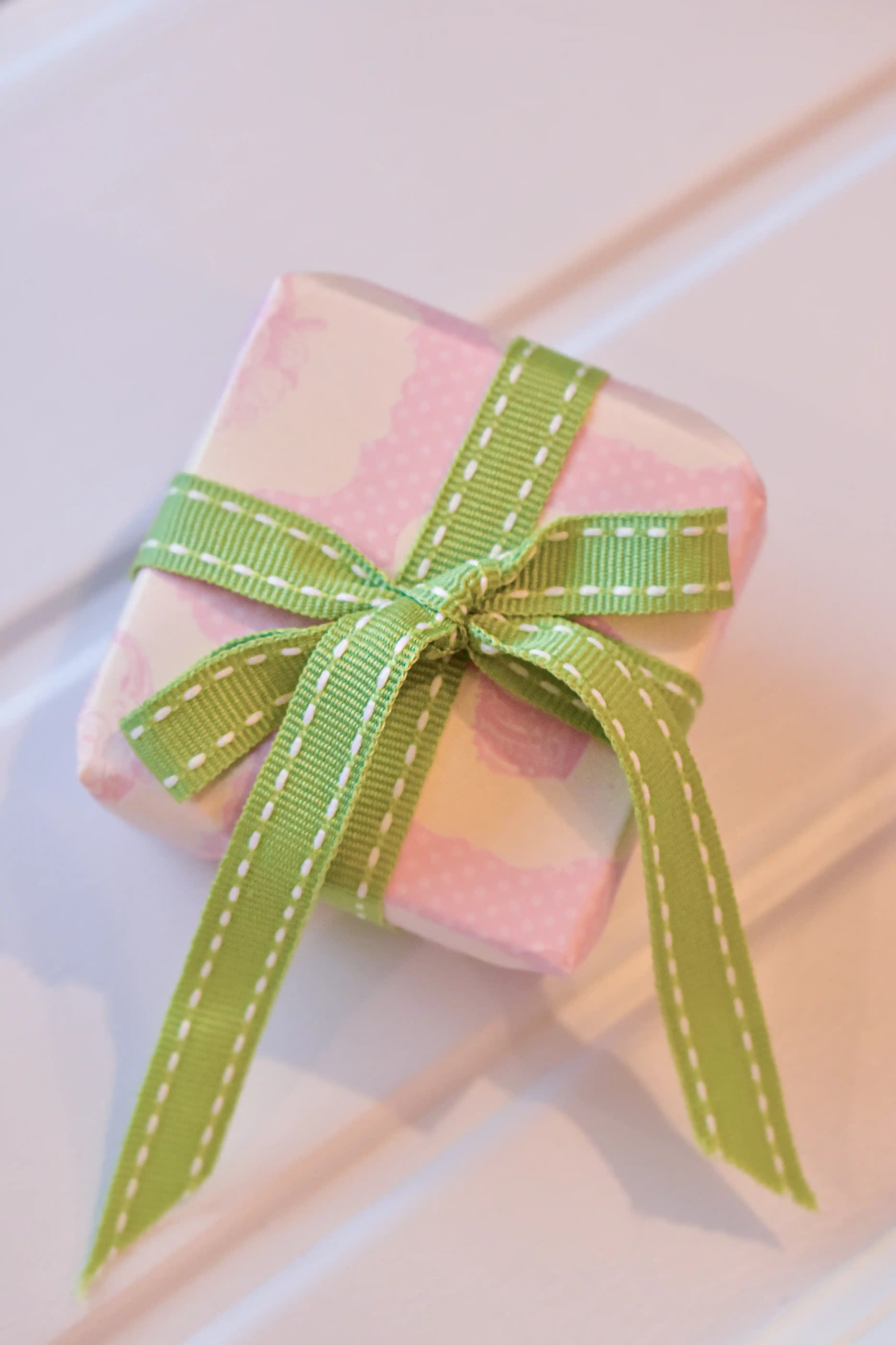 This image shows a beautifully wrapped gift box, featuring the Moss Stitch ribbon tied into a lovely bow. The pastel green ribbon adds a fresh and charming touch to the present.