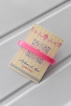 This detailed, head-on view of the Petal Satin ribbon highlights its bold pink colour and smooth satin material. The ribbon is wrapped tidily around the "Sunlit Hugs" brand tag to show its precise design.