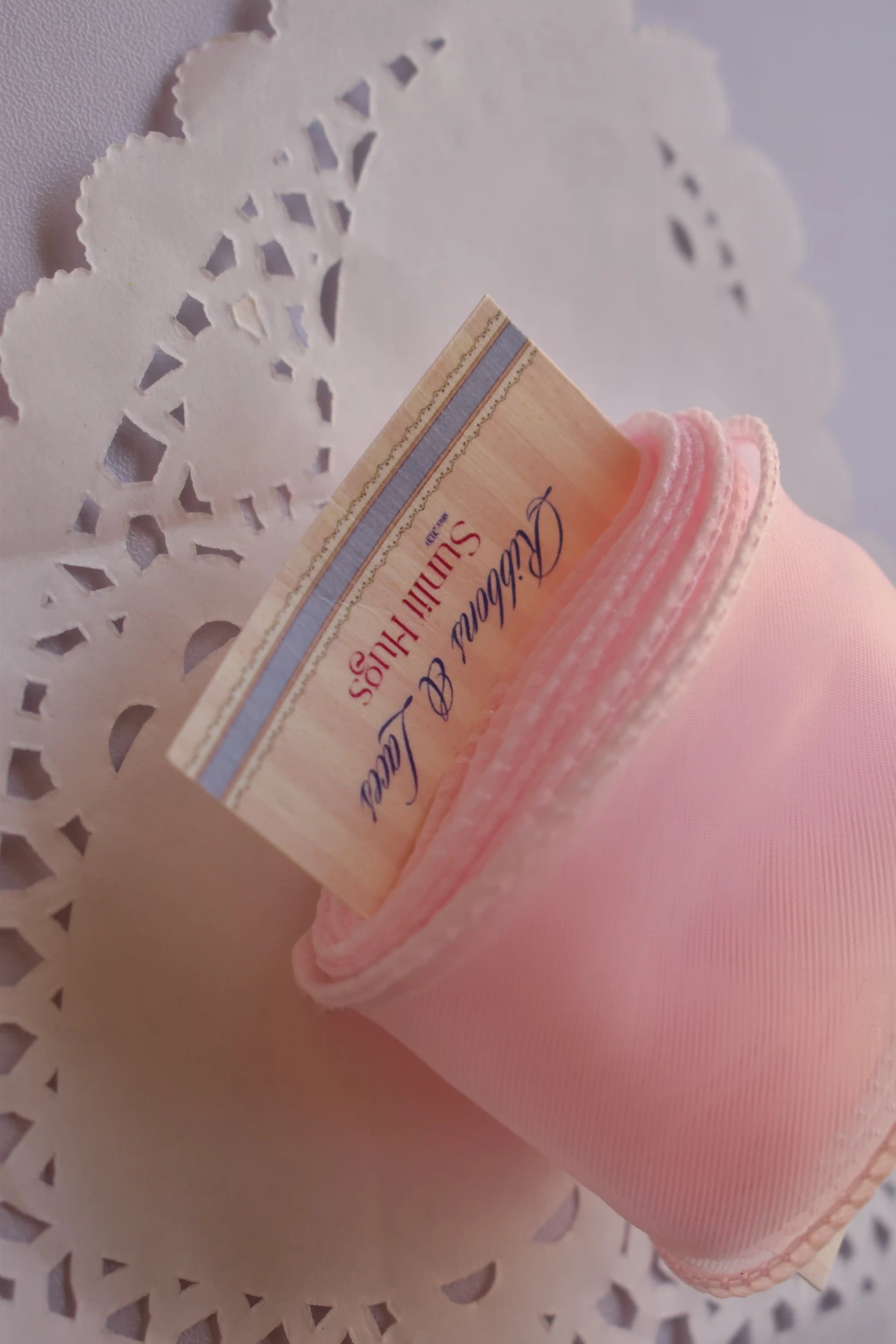Angled close-up of the wide pink sheer organza ribbon showcasing the texture and multiple layers of the material around the display card.