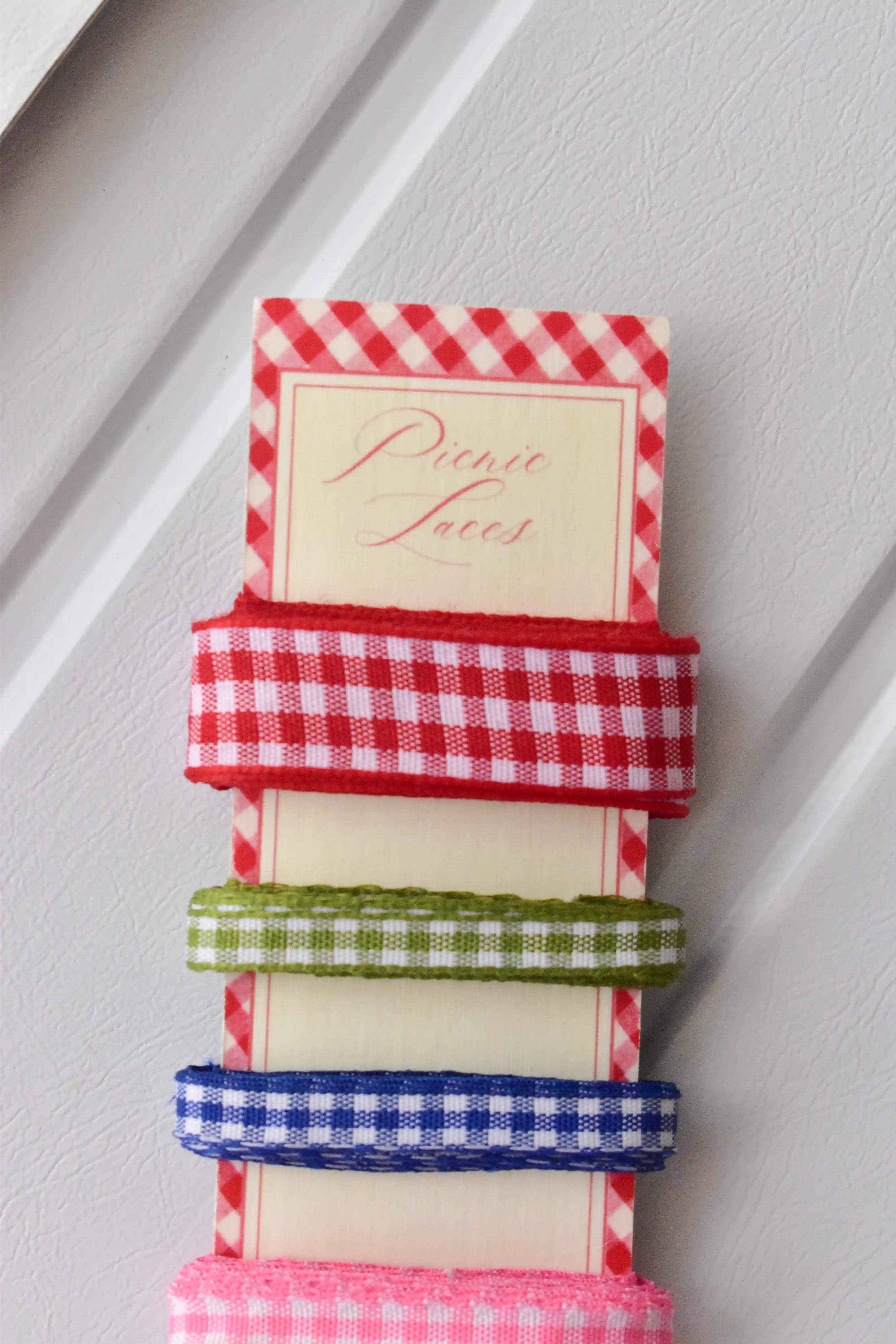 Four narrow gingham ribbons in red, green, blue, and pink, highlighting the textured weave on the 'Picnic Laces' card.