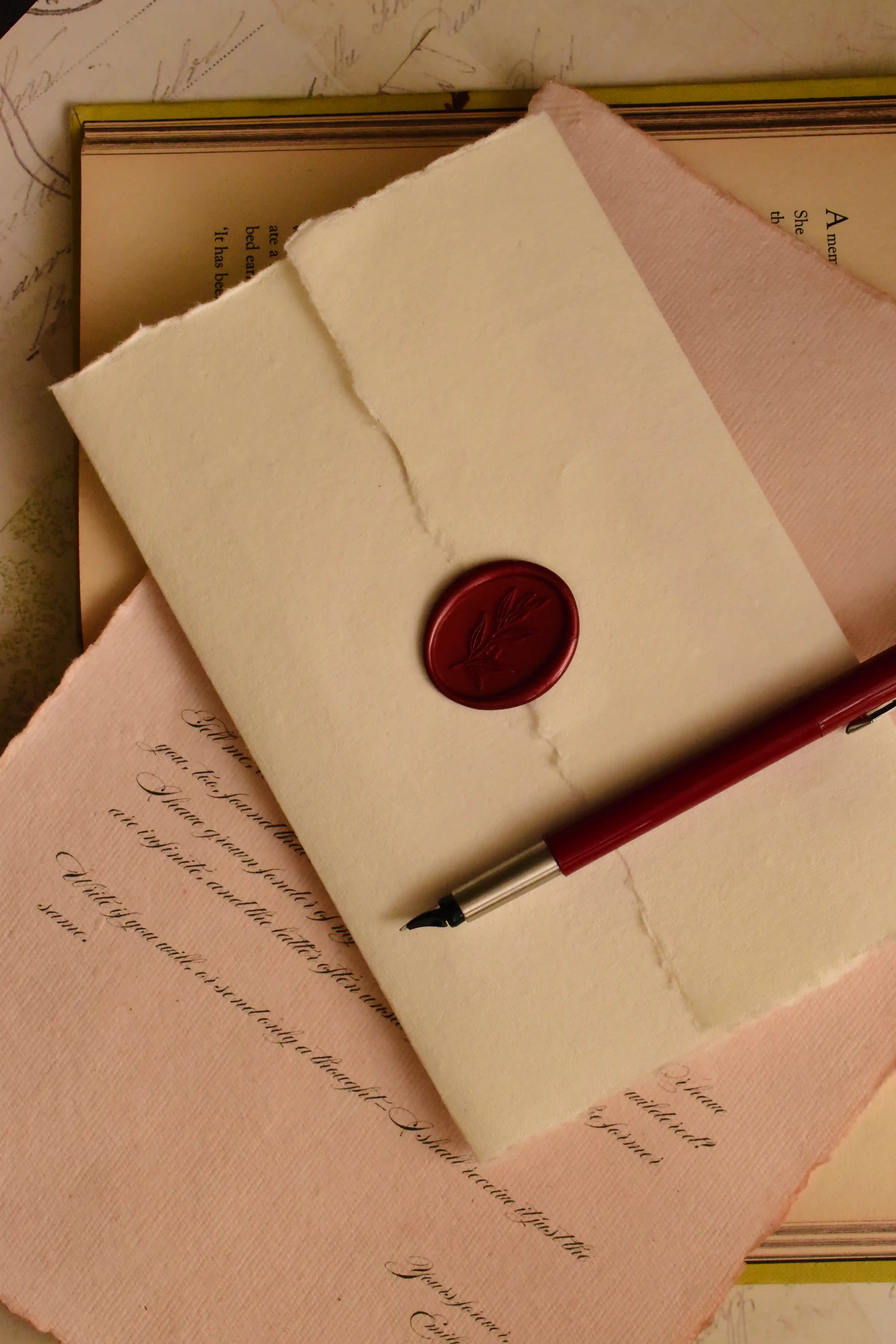 This warm, staged shot highlights the final, dramatic presentation: the scarlet wax seal securing the handmade ivory envelope, symbolizing a timeless and private act of old-world letter writing.