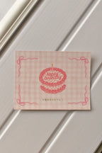 A detailed view of the postcard's front, showcasing the cute pink cake illustration and the soft pink gingham pattern that gives it a sweet, nostalgic charm.