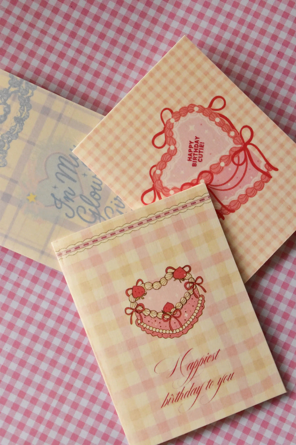 This image showcases the variety in the set, featuring the Happy Birthday Cutie heart cake card, the Happiest Birthday heart cake card, and the Glowing Girl Era plaid card, demonstrating the full range of designs.