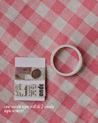 One washi tape roll and two washi tape testers featuring antique script and stamp patterns.