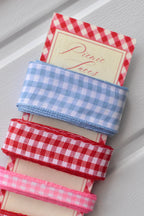 Close-up of the wide light blue, wide red, and narrow pink gingham ribbons wrapped around the top of the display card.